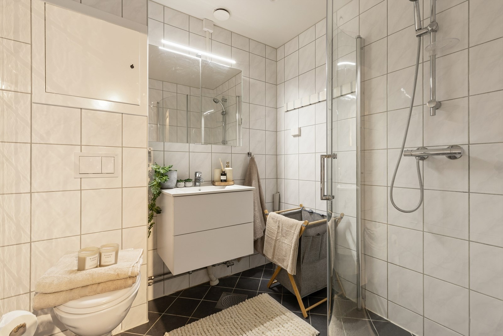 Et stilrent og fagmessig modernisert bad med varmekabler, flislagte overflater og funksjonelle løsninger - klart for komfort i hverdagen. Galleribilde