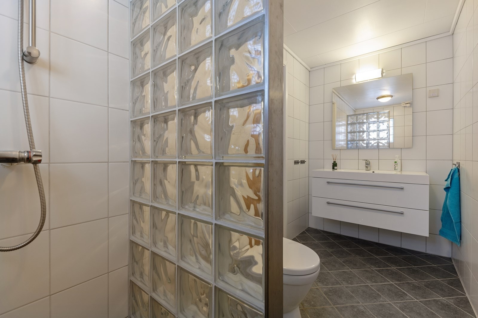 Badet har innredning bestående av servant nedfelt i baderomsmøbel, gulvstående toalett og en dusjnisje. Galleribilde