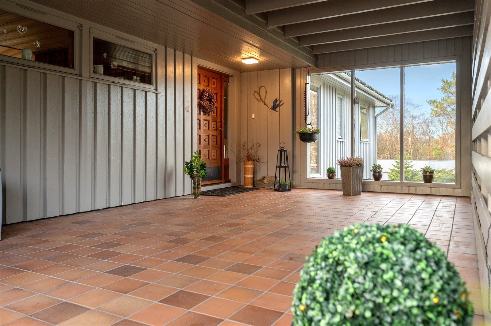 Overbygd, flislagt inngangsparti med plass til oppvaring av sykler og diverse. Galleribilde