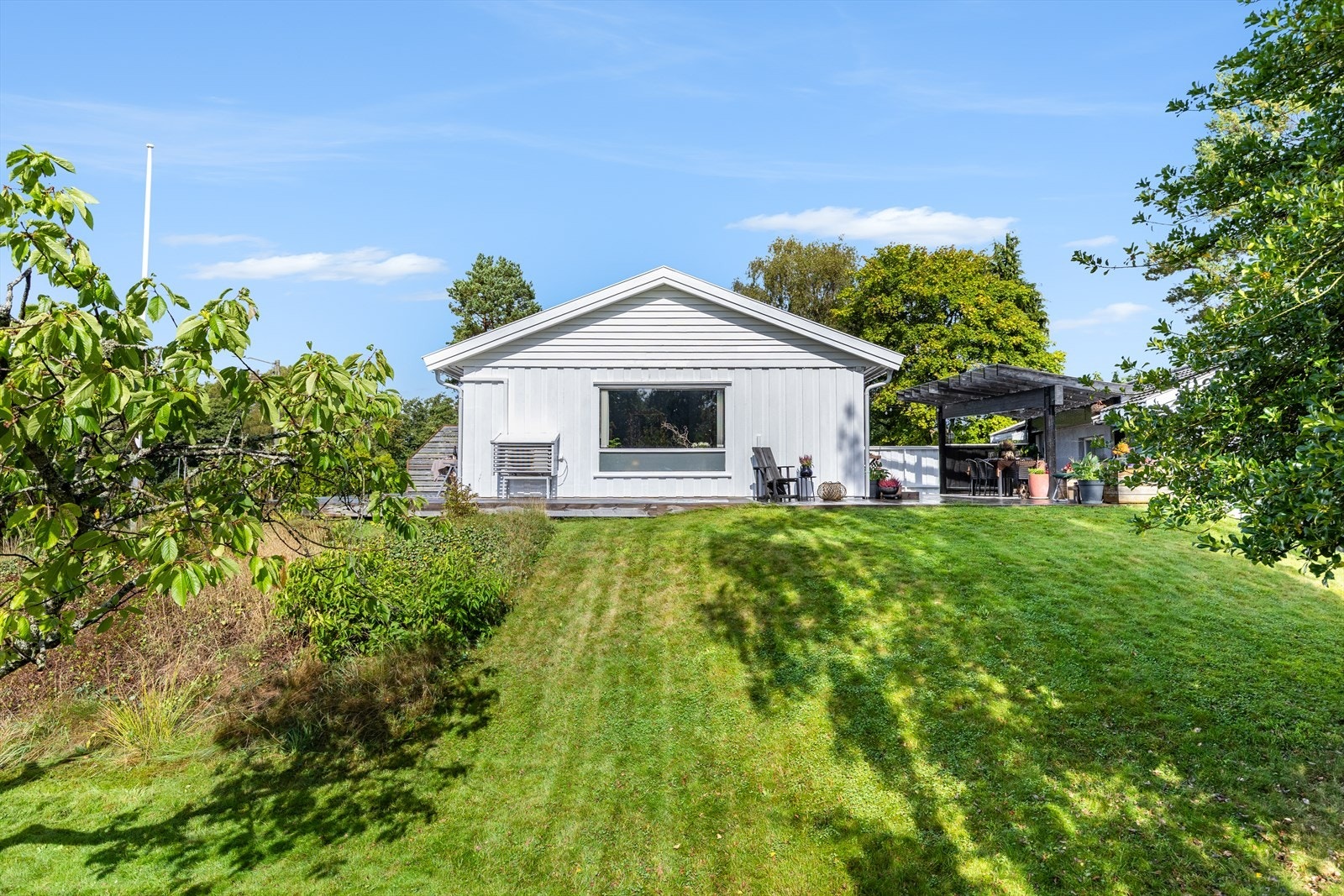 Tomten er pent opparbeidet med hage, gressplen og trær. Galleribilde