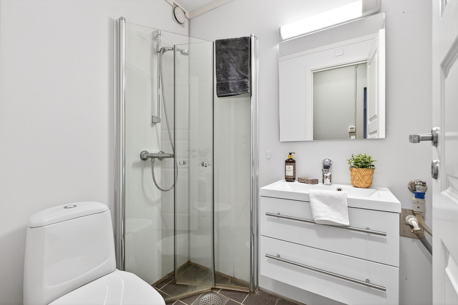 Rommet er innredet med nedfelt servant med underskap, dusjhjørne, opplegg for vaskemaskin og toalett Galleribilde