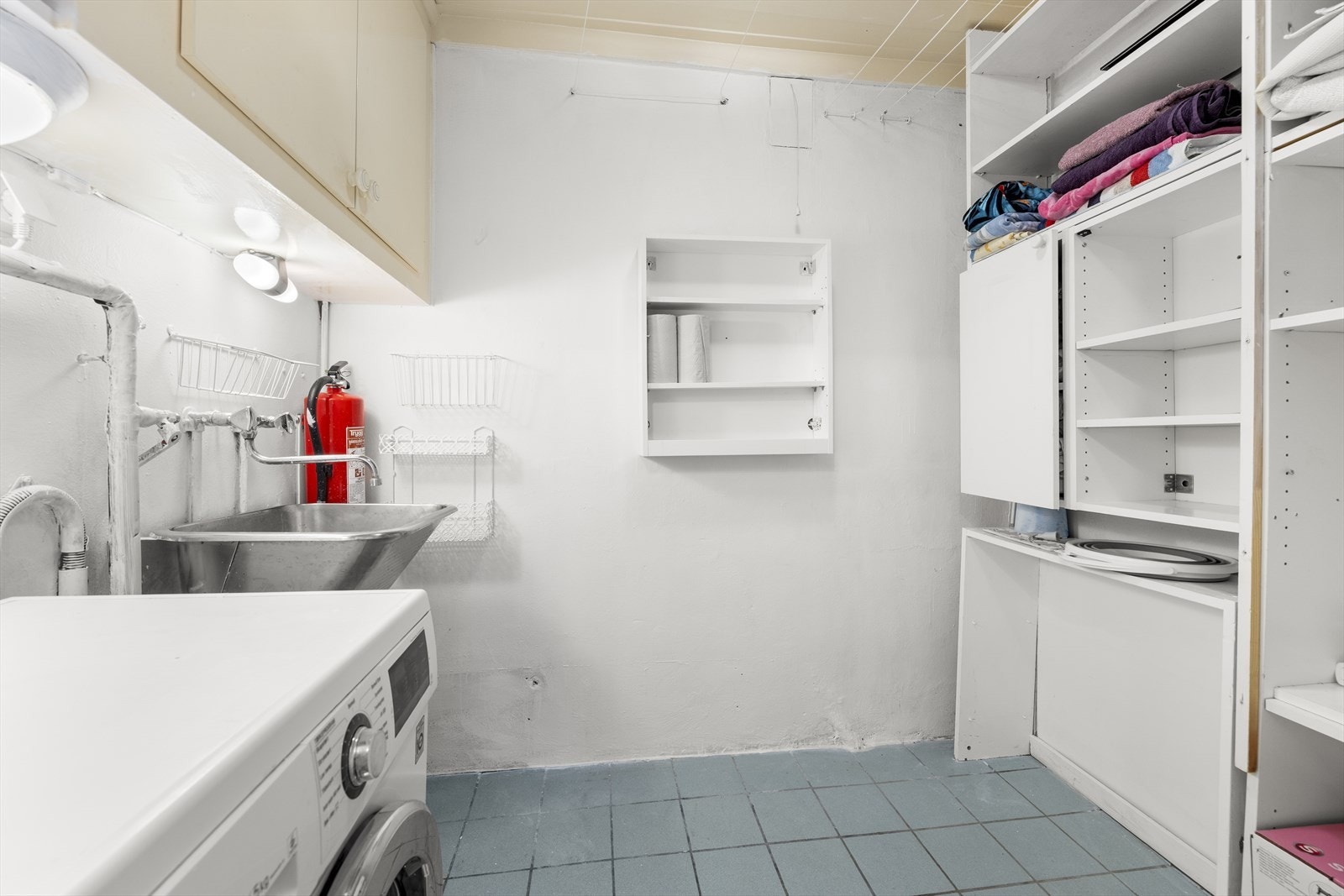 Separat og funksjonelt vaskerom med flislagt gulv og opplegg for vaskemaskin. Galleribilde