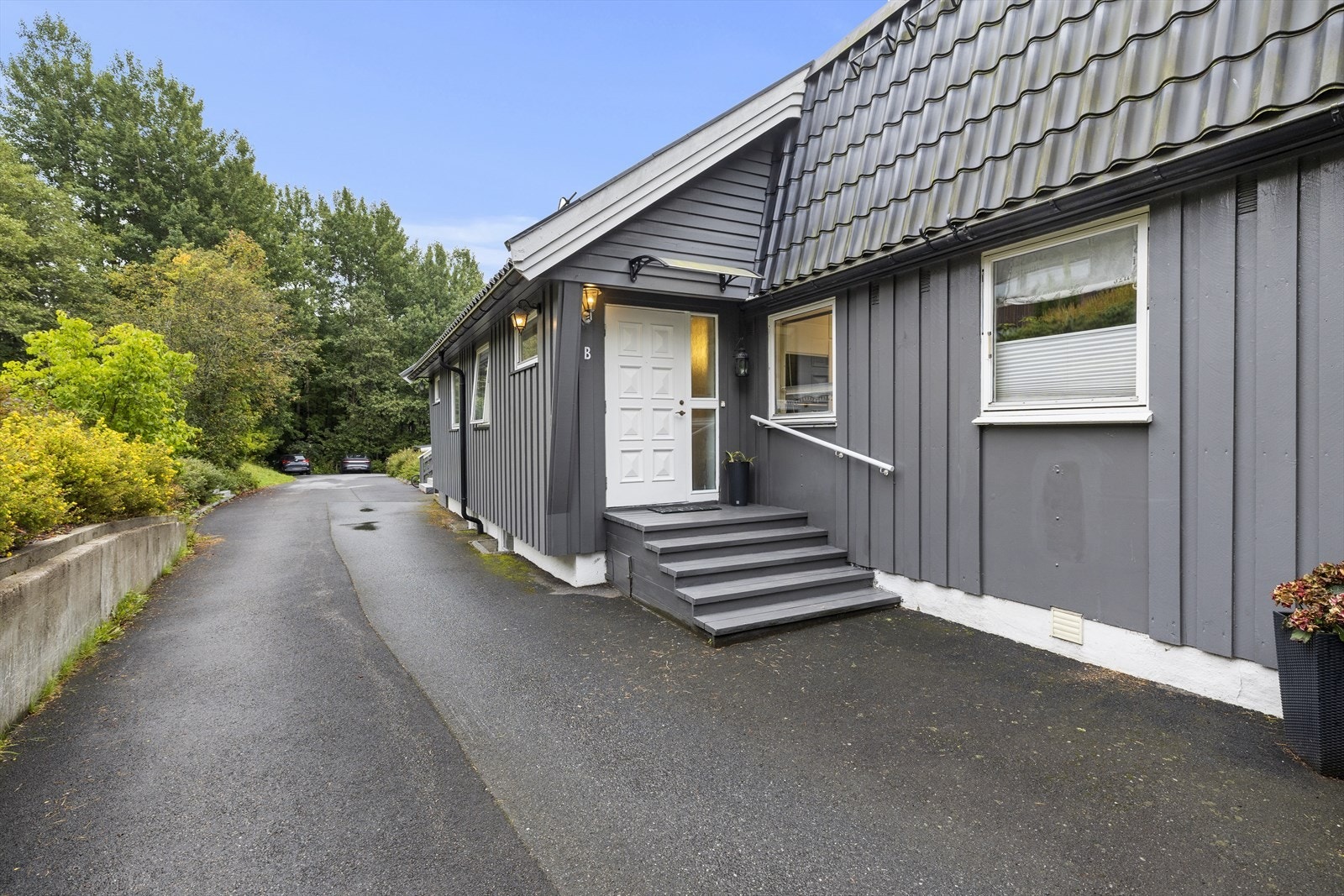 Et innbydende inngangsparti med en klassisk og solid hovedytterdør i teak. Galleribilde