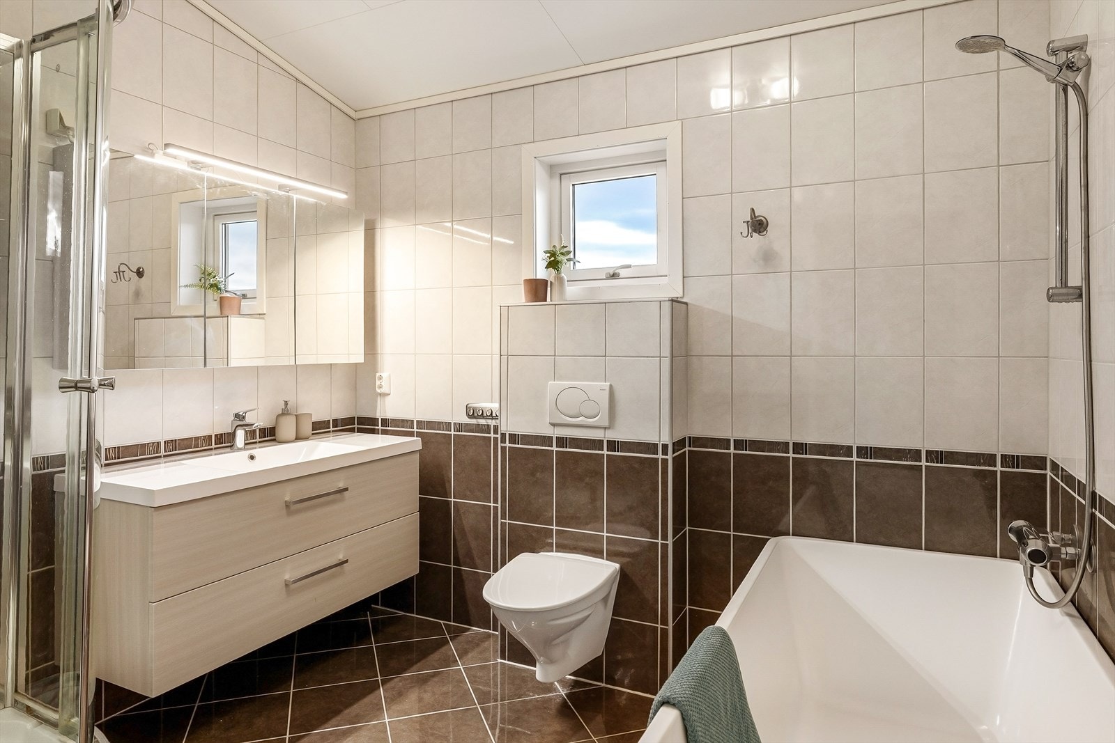 Helfliset bad med vegghengt toalett, dusjkabinett og et herlig badekar. Galleribilde