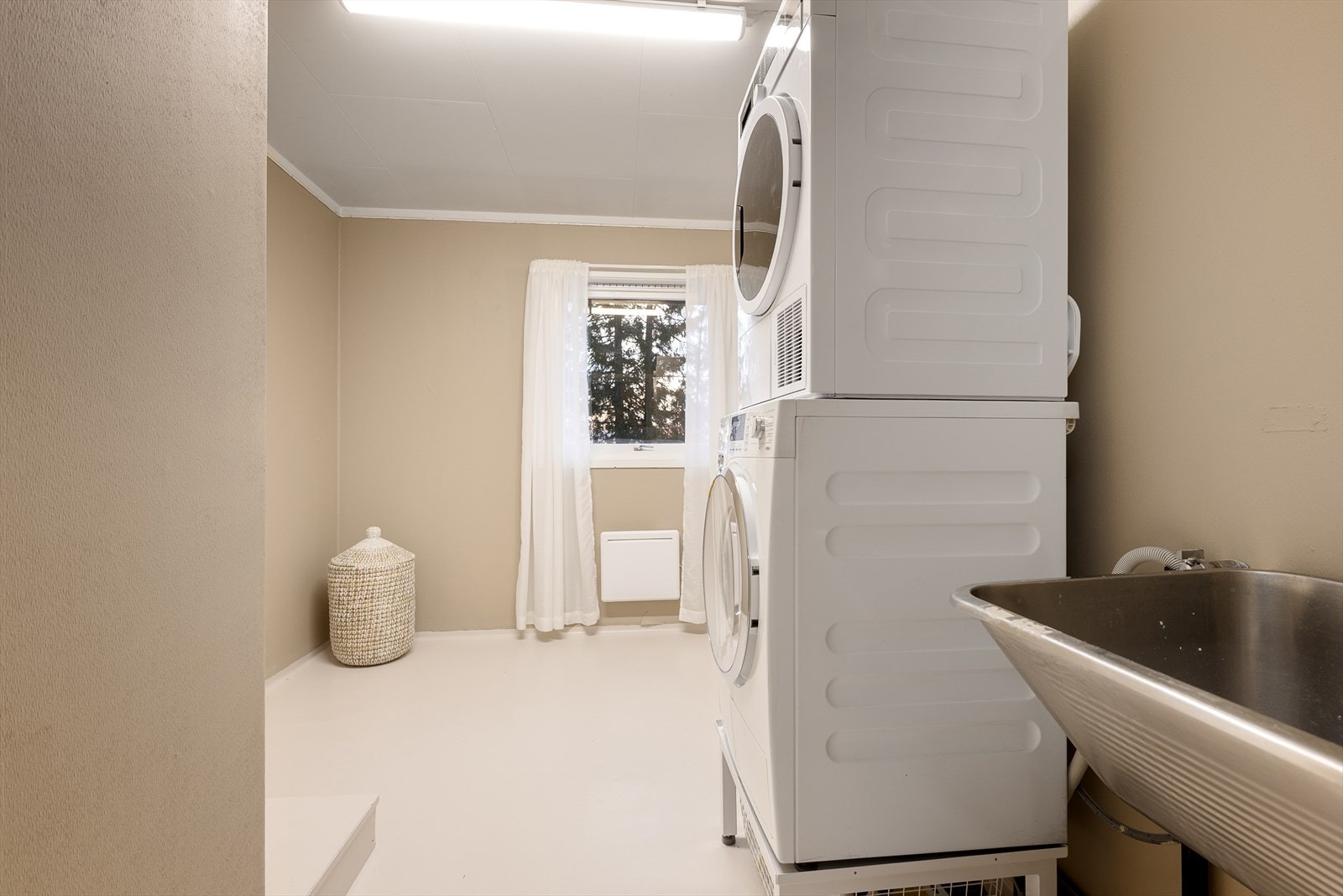 Separat og praktisk vaskerom med våtromsbelegg på gulv og opplegg for vaskemaskin. Galleribilde