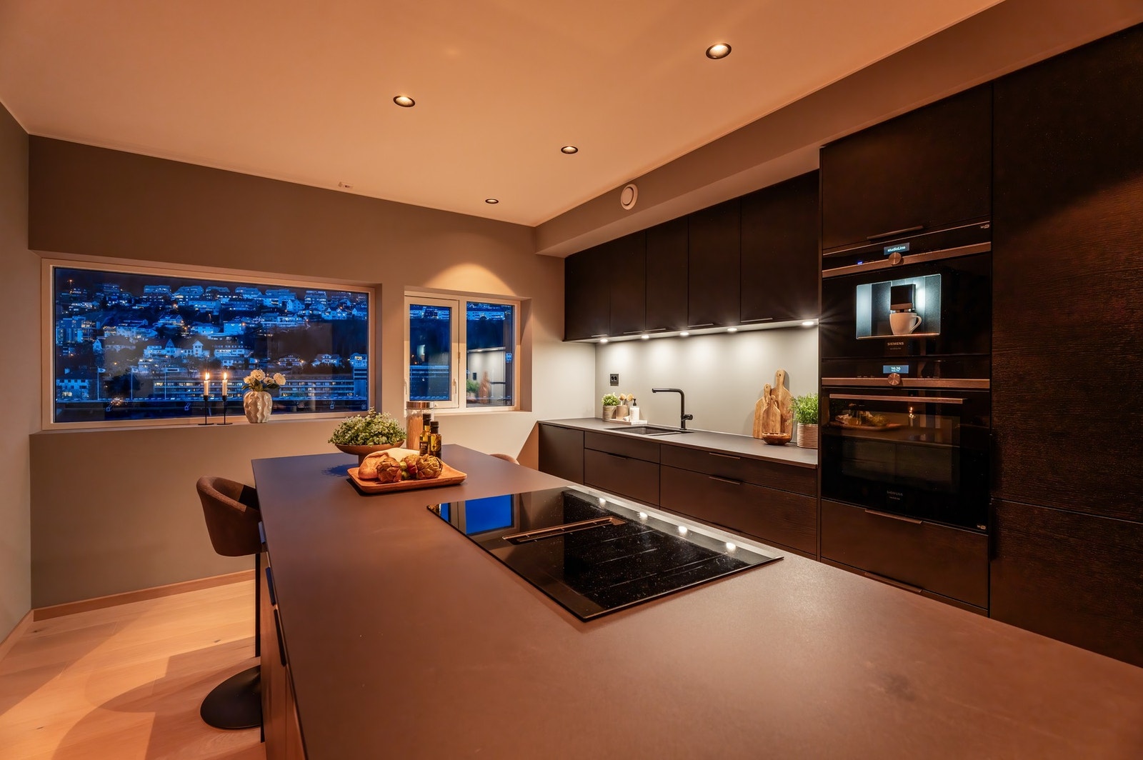 Kjøkkenet er stilfullt innredet i sort, med integrerte hvitevarer og en benkeplate i stein som gir et moderne og eksklusivt preg. Galleribilde