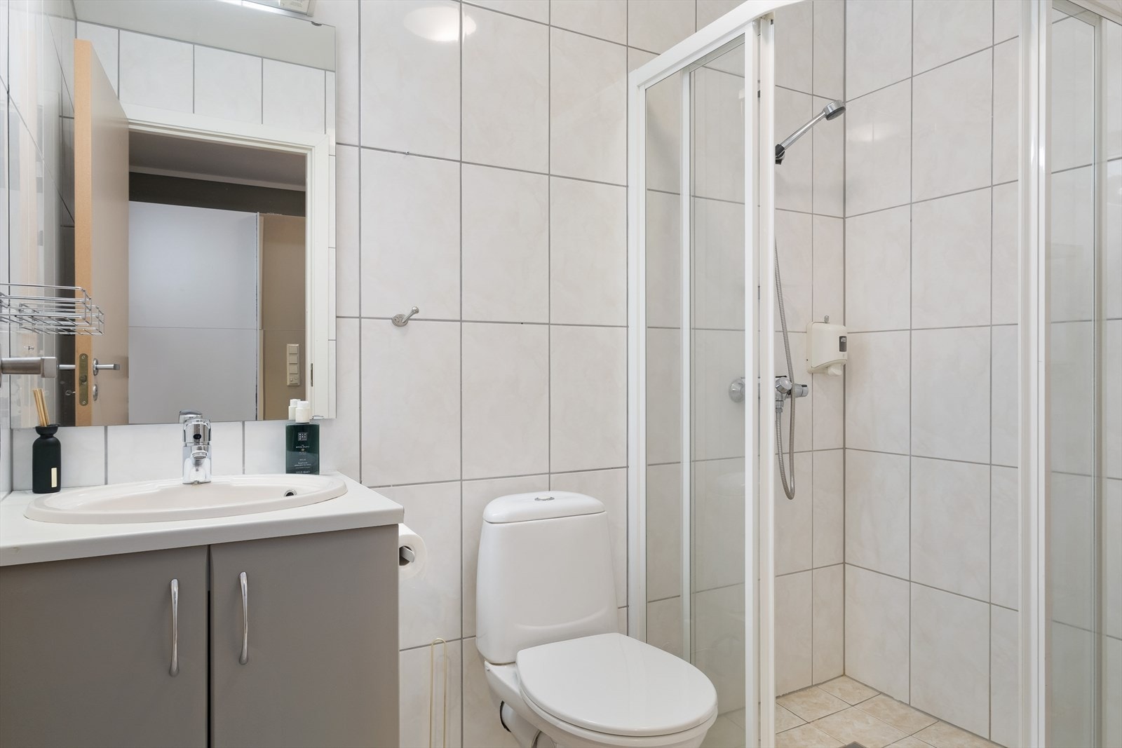 Baderommet som er utstyrt med klosett, nedfelt servant med underskåp, spegel og dusjhjørne med skyvedører. Galleribilde