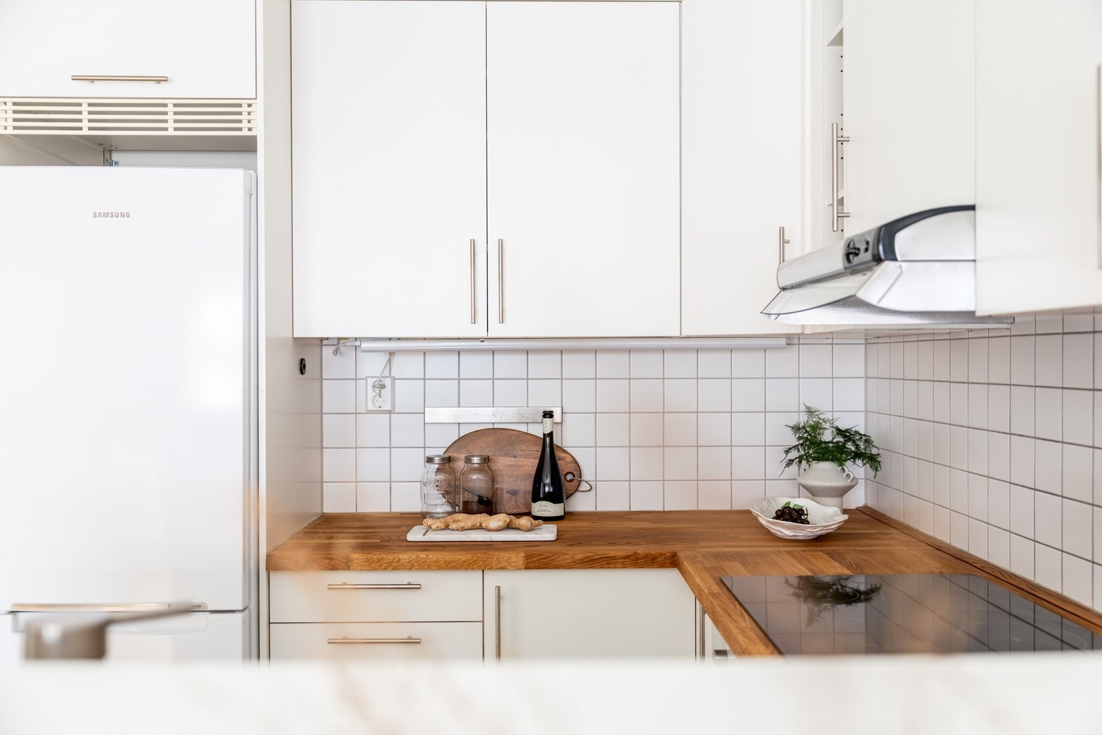 - Kjøkkeninnredning med glatte fronter og benkeplate. Det er flislagt mellom benkeplate og overskap - Galleribilde