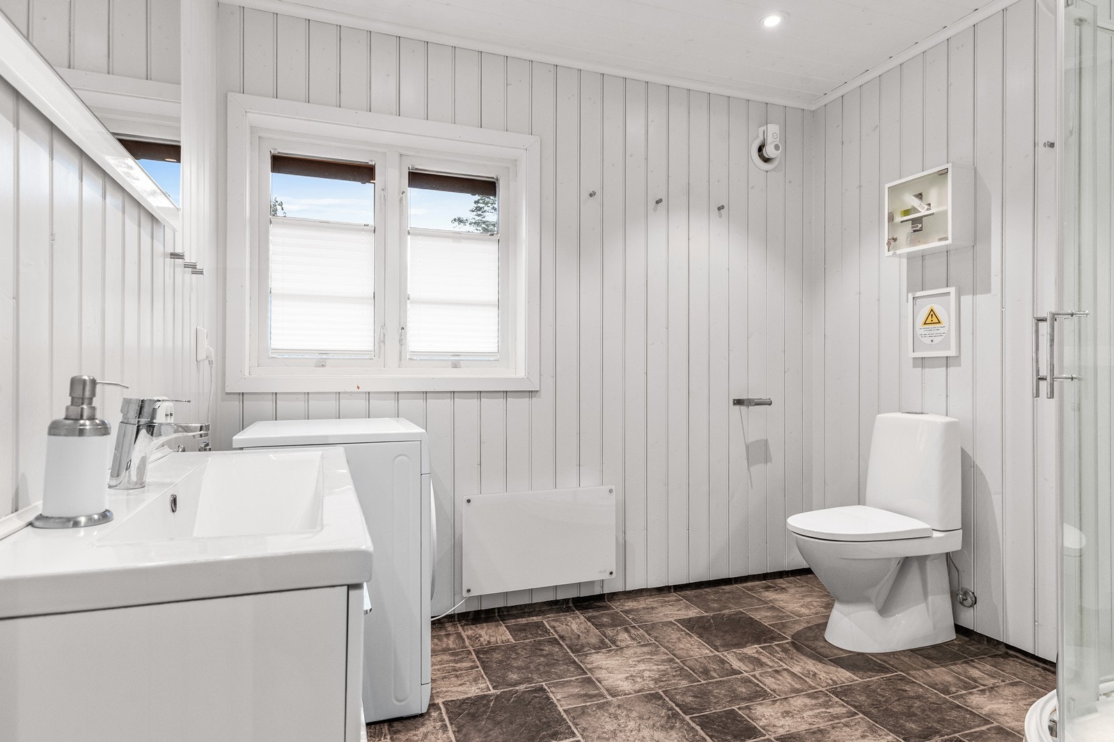 Badet er lyst og funksjonelt med servantinnredning, toalett og dusjkabinett. Galleribilde