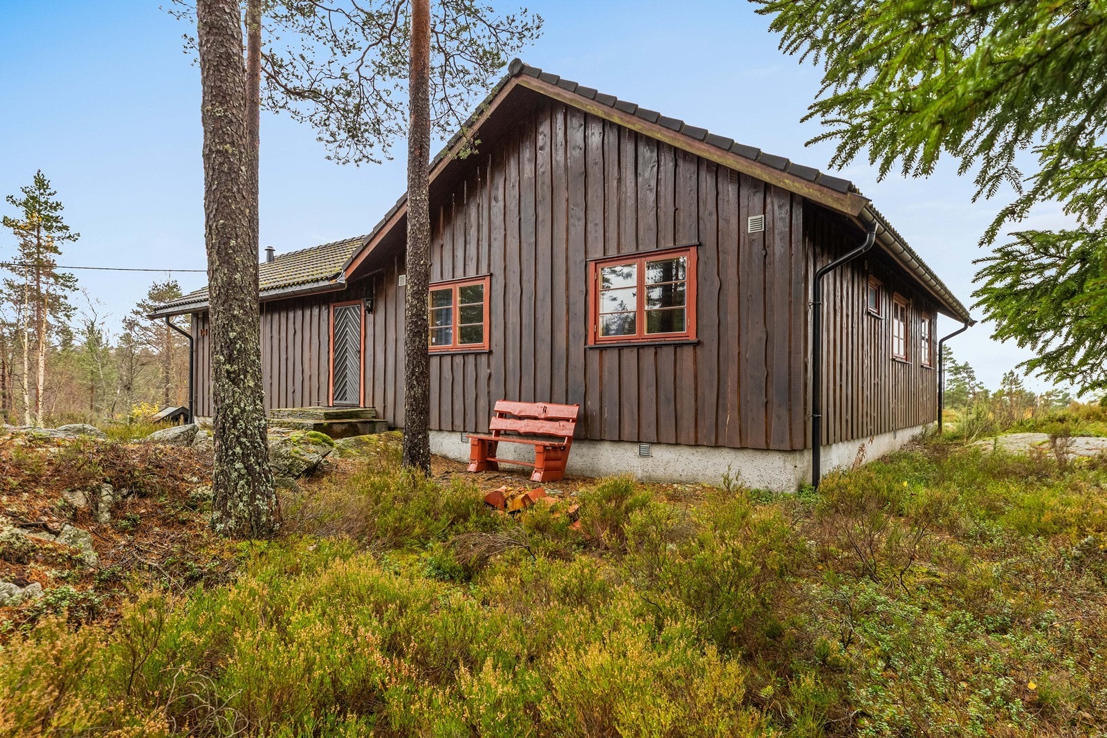 Hytta er plassert på en lett skrånende naturtomt, pent integrert i terrenget. Galleribilde