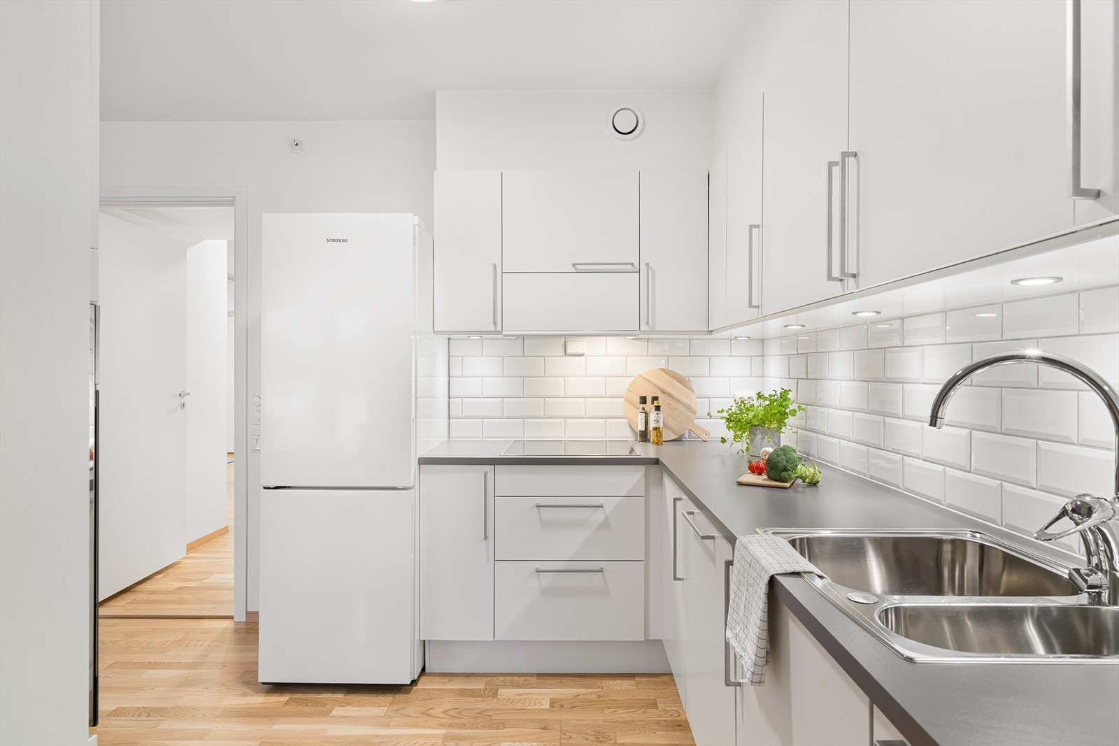 Hvitt klassisk kjøkken med veldig god lagringsplass i skuffer og skap. Fliser og god belysning over benk. I Galleribilde