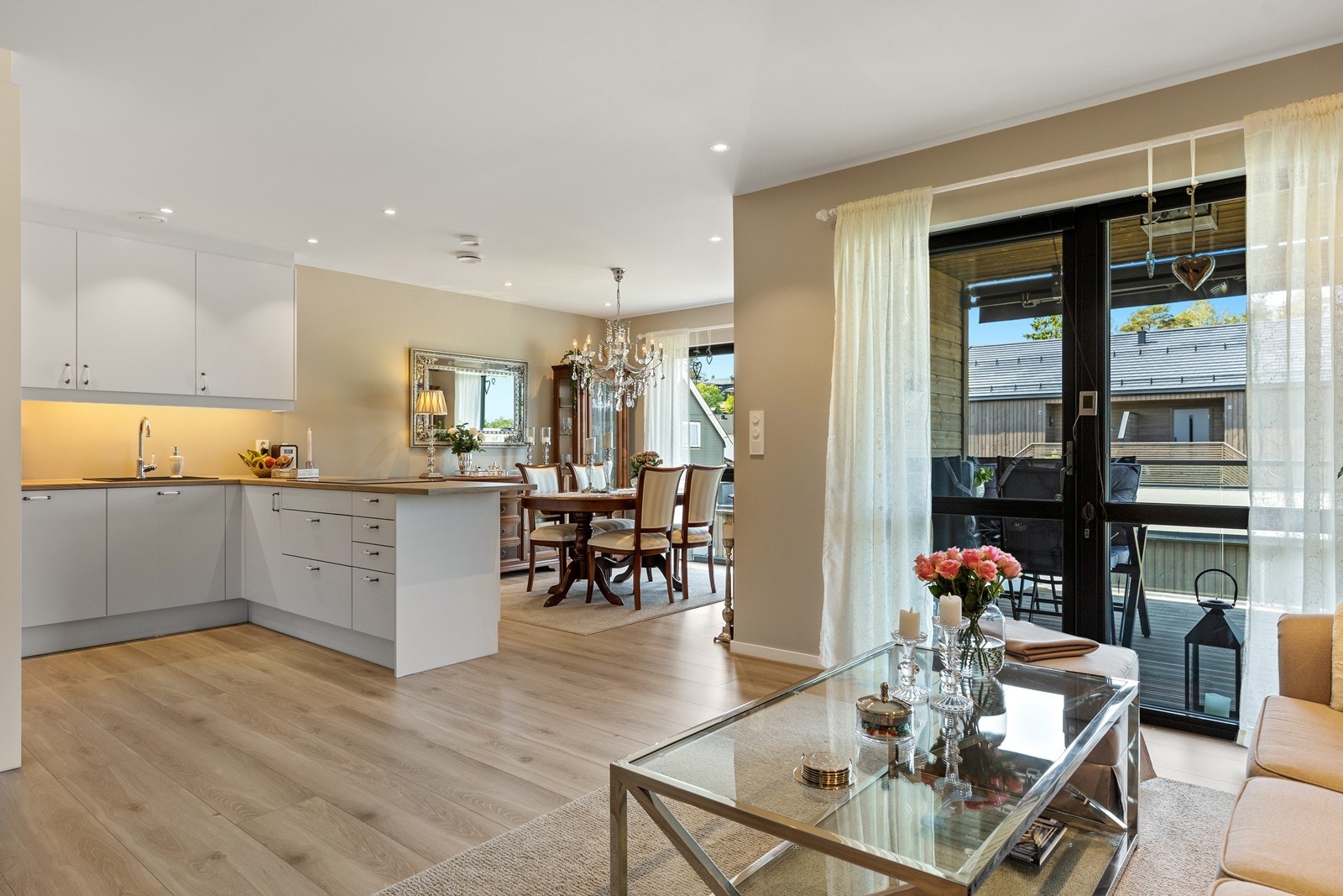 Stuen har et lunt og moderne uttrykk med slette vegger malt i en dus beigetone og laminatgulv som gir en varm og helhetlig atmosfære. Rommet har god plass til både sofagruppe og spisebord, og store vindusflater slipper inn rikelig med naturlig lys. Galleribilde