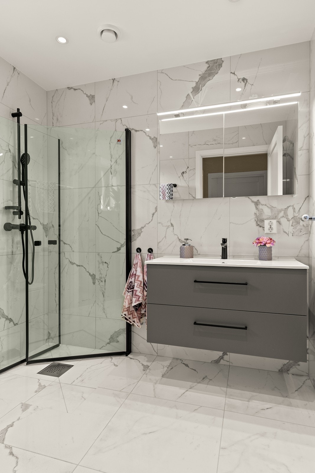 Bad i 2. etasje er helfliset med elegante marmorfliser på både gulv og vegger, og har slett malt himling med spotter. Her finner du grå baderomsinnredning med skuffer og heldekkende servant. Galleribilde