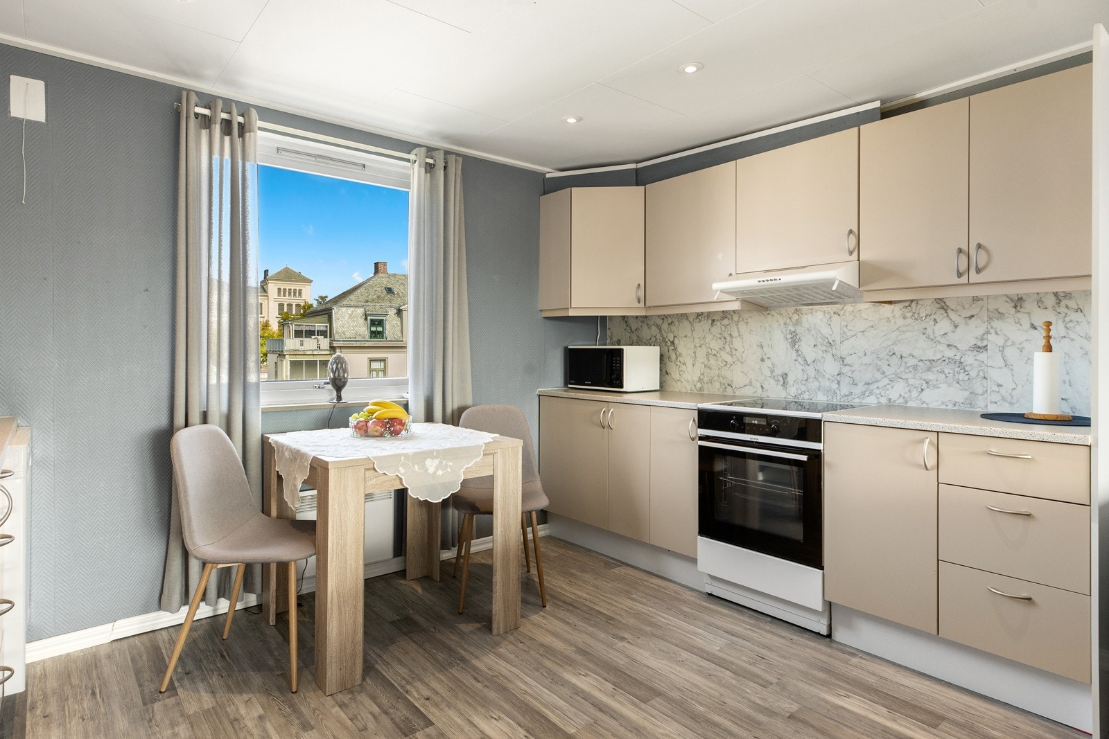 Kjøkkenet har en åpen løsning mot stuen, med gjennomgående lys som gir en lys og trivelig atmosfære. Innredningen er stilren med slette fronter og laminat benkeplate, samt dekorative plater med marmorpreg mellom benk og overskap. Galleribilde