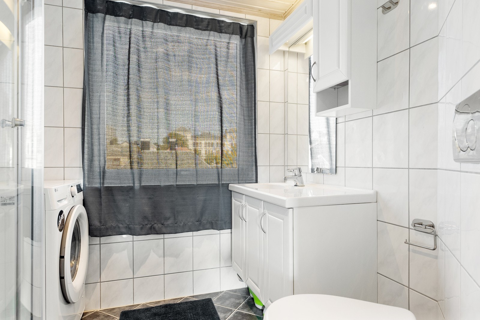 Flislagt bad som ble oppgradert i regi av borettslaget i 2009. varmekabler i gulv. Hvit innredning med heldekkende servant, speil og sideskap. Praktiske løsninger som vegghengt toalett, dusjkabinett og opplegg for vaskemaskin gjør badet brukervennlig. Galleribilde