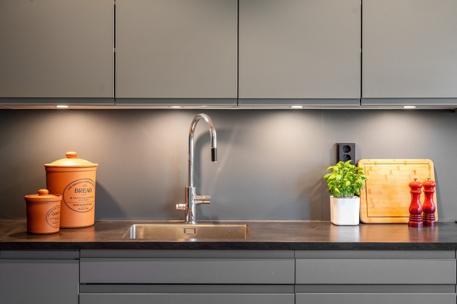 Den mørke laminatbenkeplaten med nedfelt stålvask og lekkert blandebatteri gir et gjennomført preg. Galleribilde