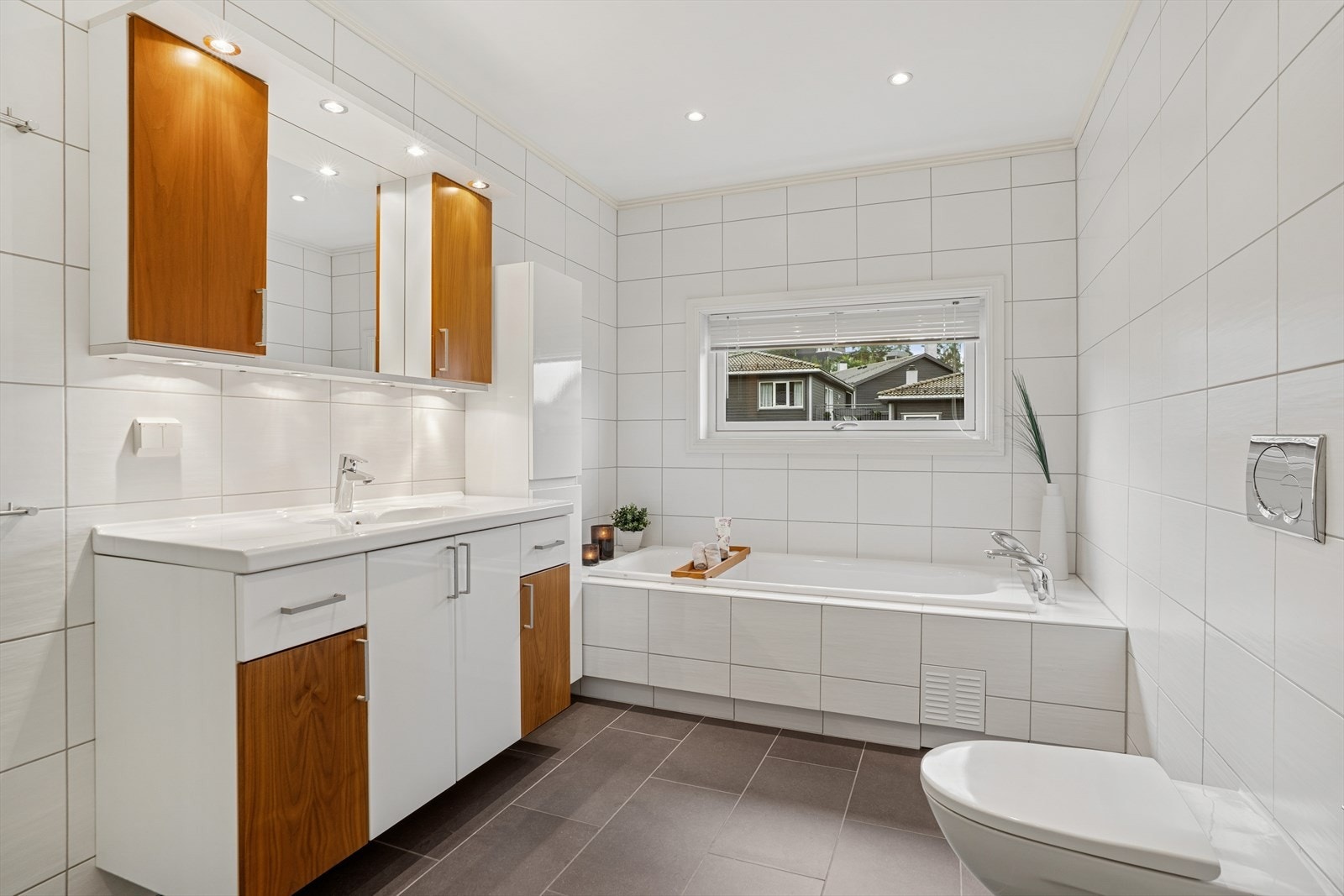 Rommet er innredet med baderomsmøbel med slette, lyse og valnøttfargede fronter, samt speil med integrert belysning. Galleribilde