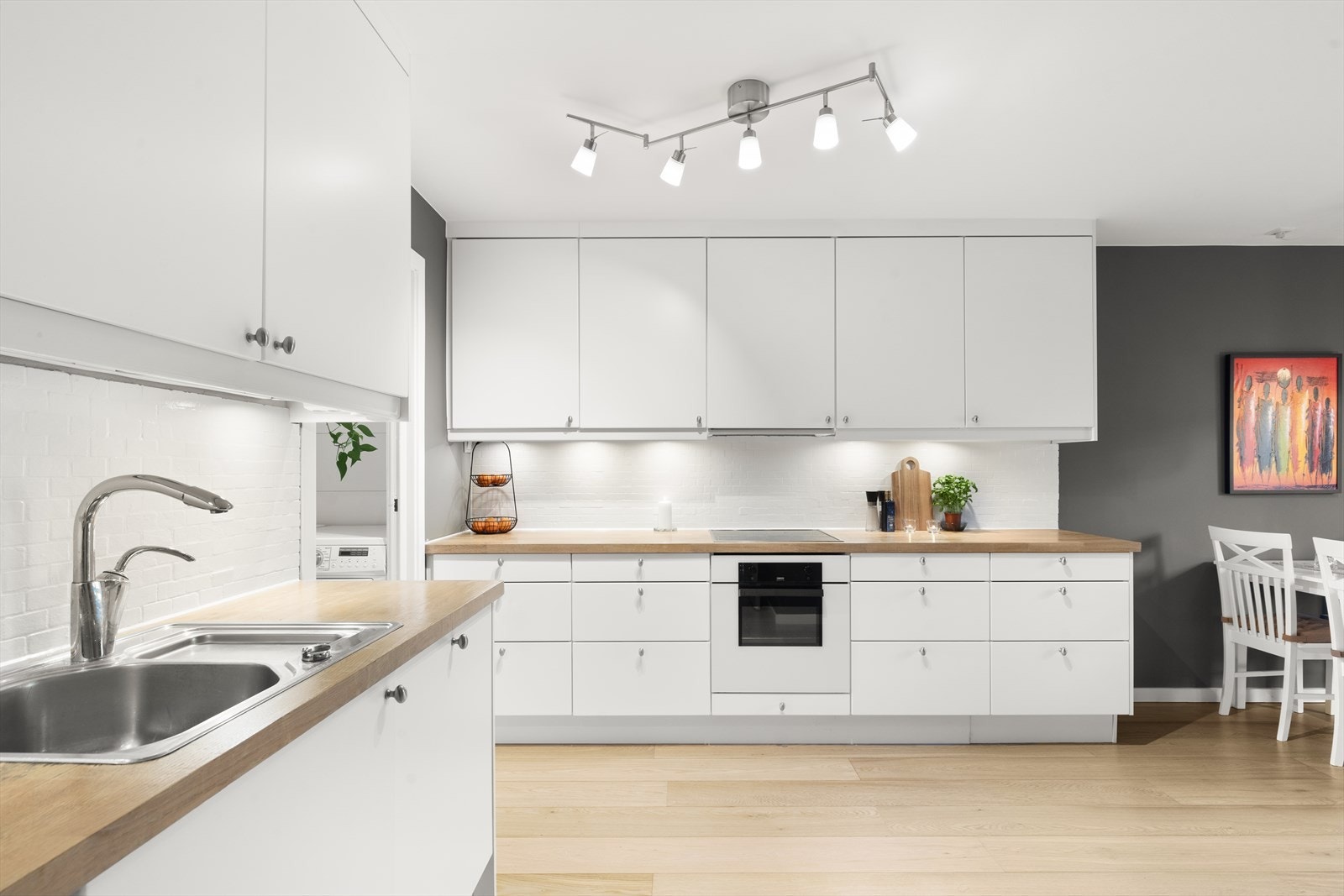 Lys og velholdt kjøkkeninnredning med glatte fronter fra 2007. Heltre benkeplate med nedfelt kum i rustfritt stål. Kullfilterventilator. Flisetterligning på vegg over benkeskap. Stekeovn, platetopp, oppvaskmaskin og kjøl/frys er integrert i innredningen. Galleribilde