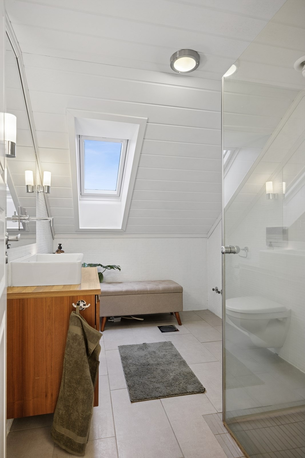 Badet er utstyrt med dusjhjørne, vegghengt toalett og et takvindu som gir godt lys. Galleribilde