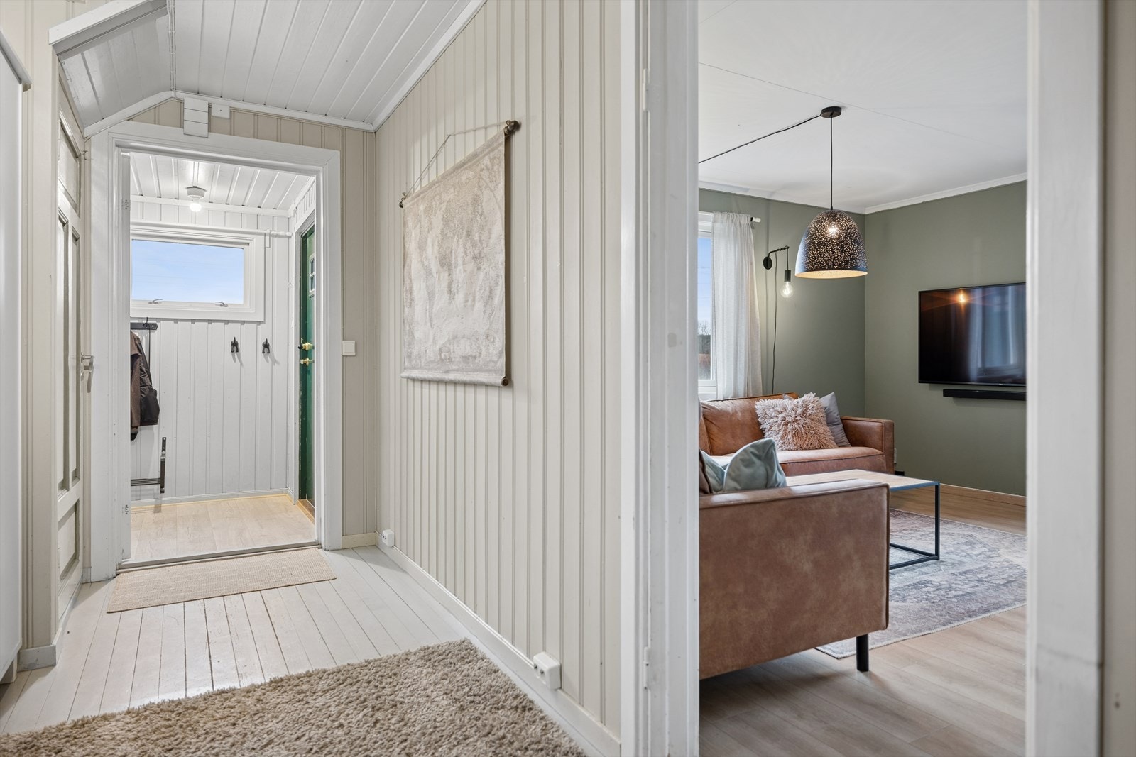 Velkommen inn i en lys gang som leder videre inn i boligens oppholdsrom. Galleribilde