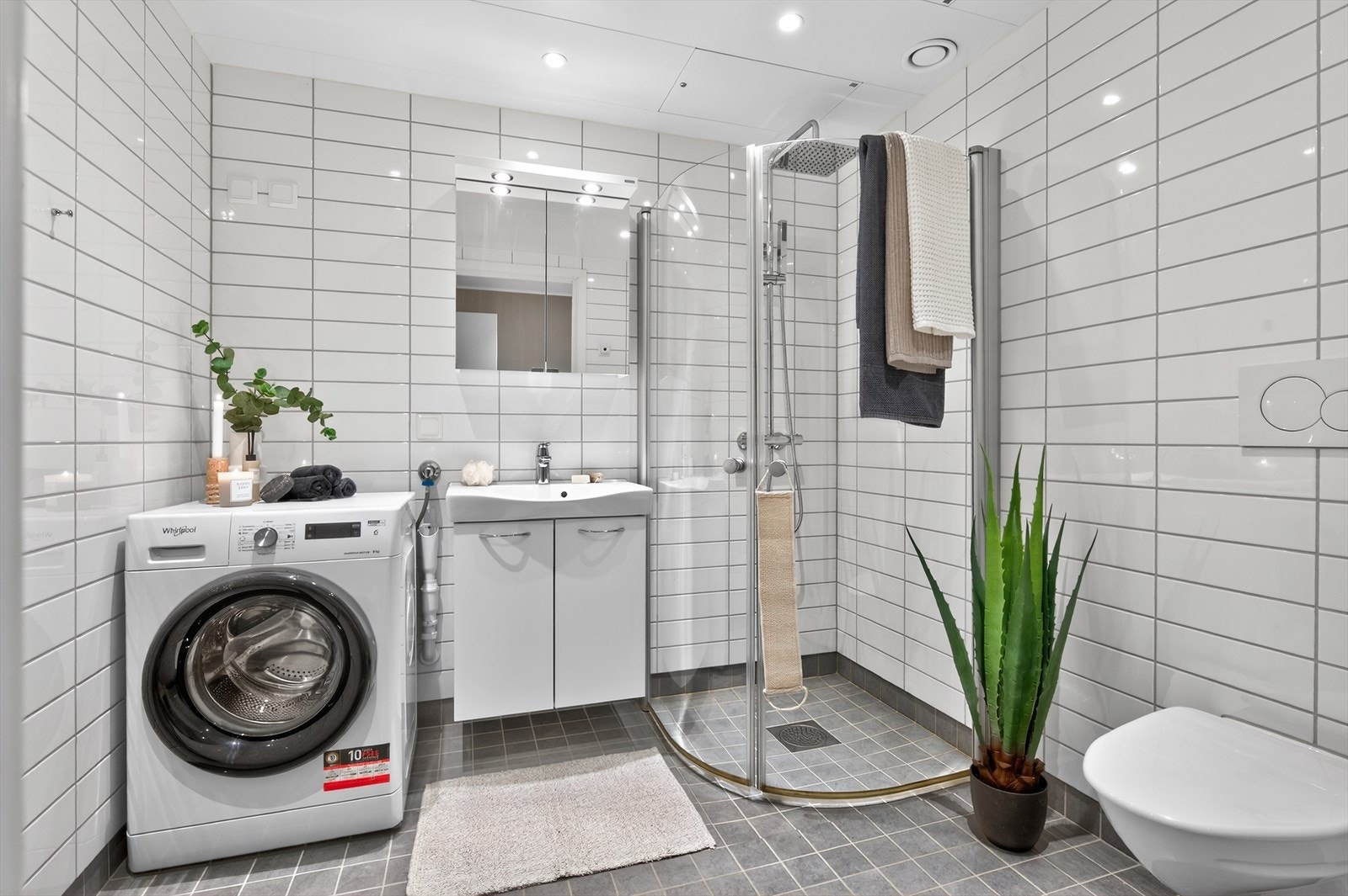 Delikat og romslig bad på ca. 5 kvm med flislagte overflater, behagelig gulvvarme og downlights i himlingen. Badet er utstyrt med vegghengt WC og har praktisk plass til både vaskemaskin og tørketrommel. Galleribilde