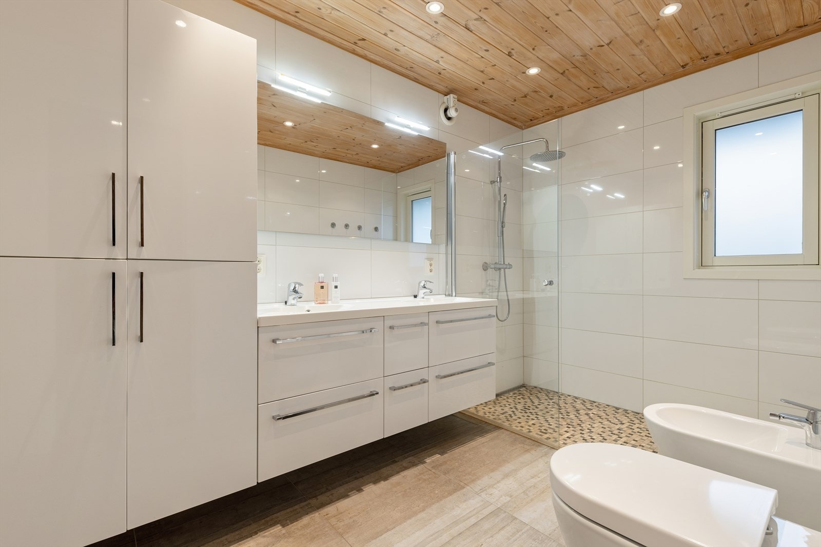 Badet er ellers utstyrt med dusjhjørne, vegghengt toalett, bidé og baderomsinnredning med god lagringsplass og nedfelt servant. Galleribilde