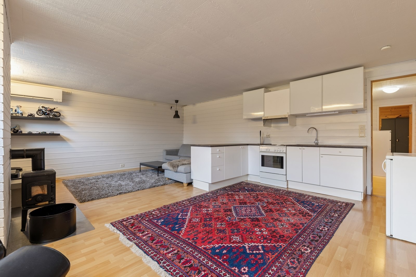 I kjelleren finner man et stort rom innredet som stue og kjøkken. Kjøkkenet er tidløst innredet med hvite, slette fronter og mørk benkeplate i laminat. Også her har man god lagringsplass og gode arbeidsflater på benk (se punkt "ferdigattest"). Galleribilde