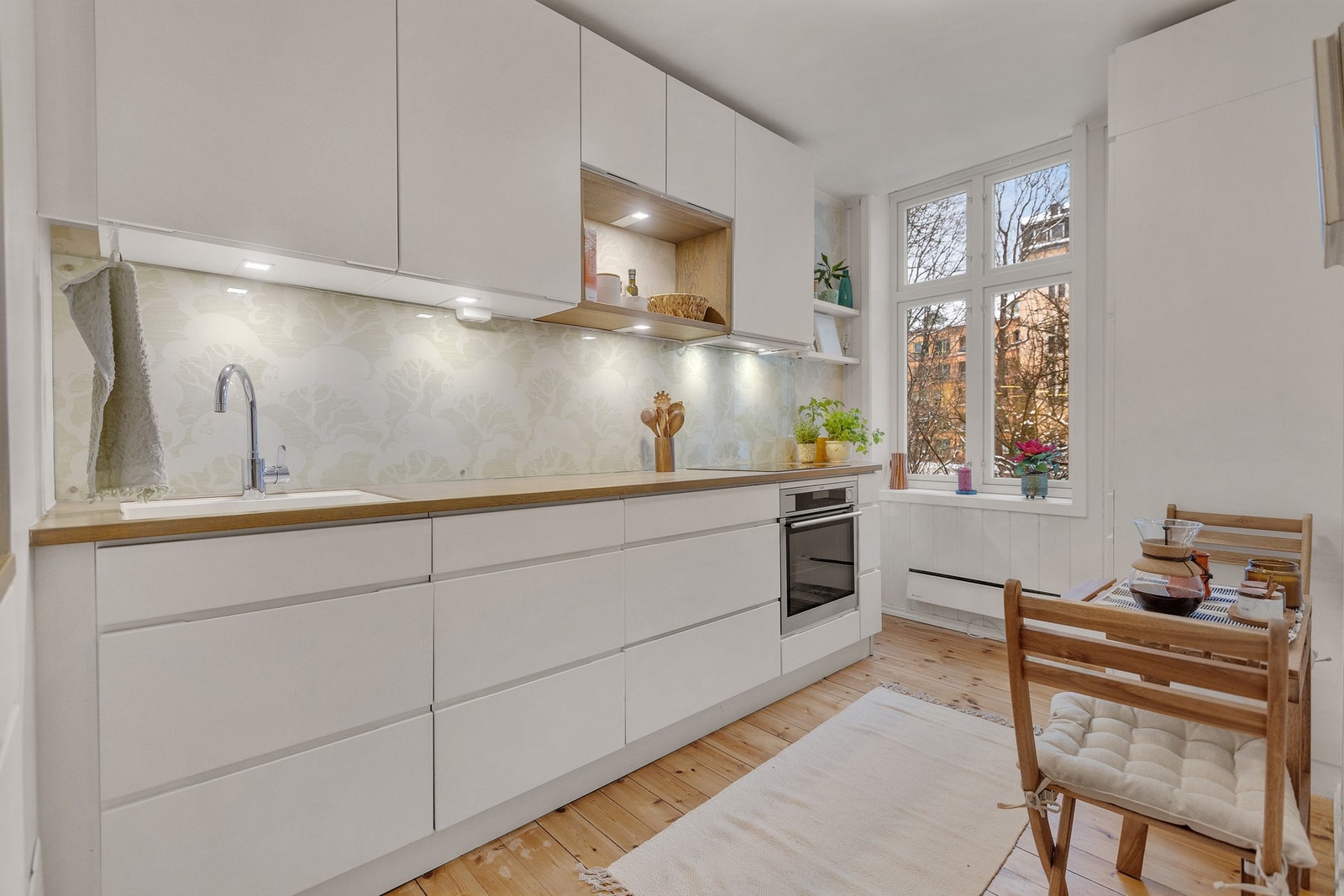 Kjøkkeninnredning fra Kvik med slette lakkerte fronter, heltre benkeplate
med glassplater på bakvegg Galleribilde