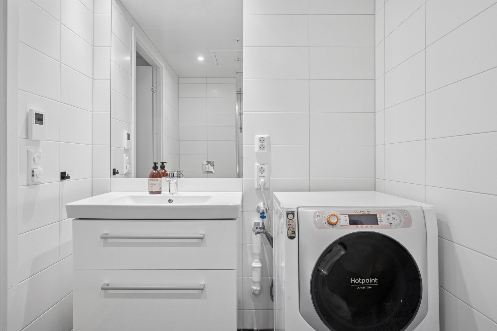 Vegghengt servantskap med skuffer. Ovenpåliggende servant med ett-greps armatur. Innmurt speil på vegg over servant. Opplegg for vaskemaskin og tørketrommel. Galleribilde