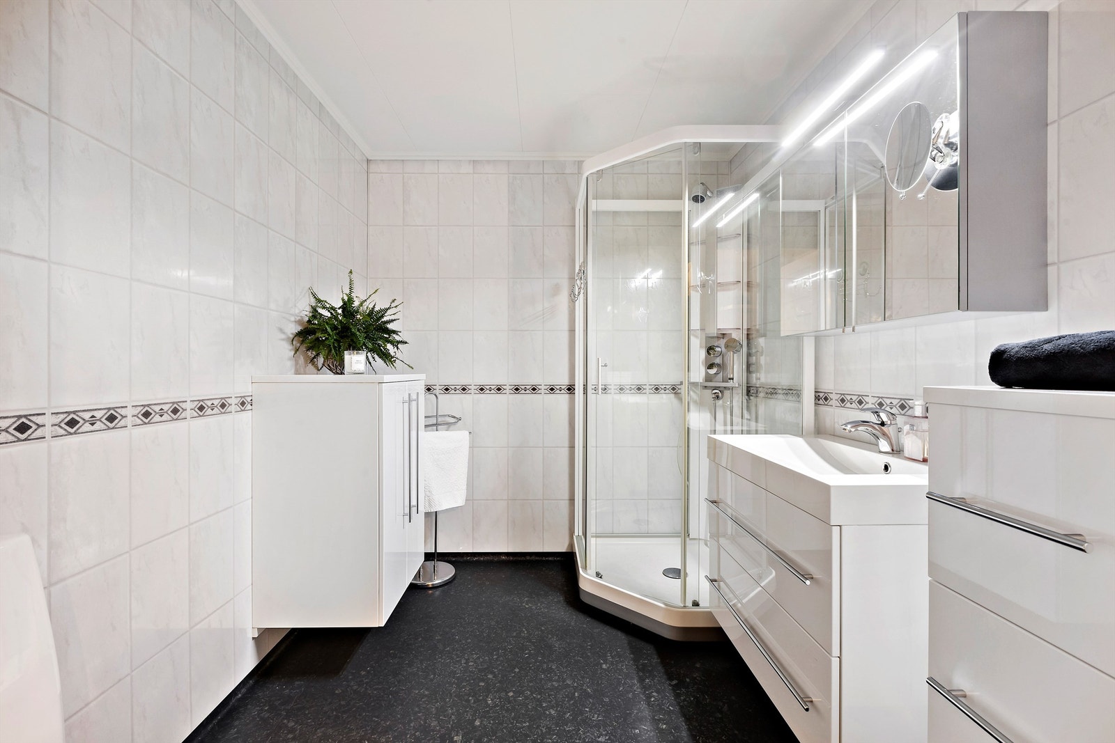 Bad i 1. etasje har vinylbelegg på gulvet, baderomsplater på veggene og dusjkabinett Galleribilde