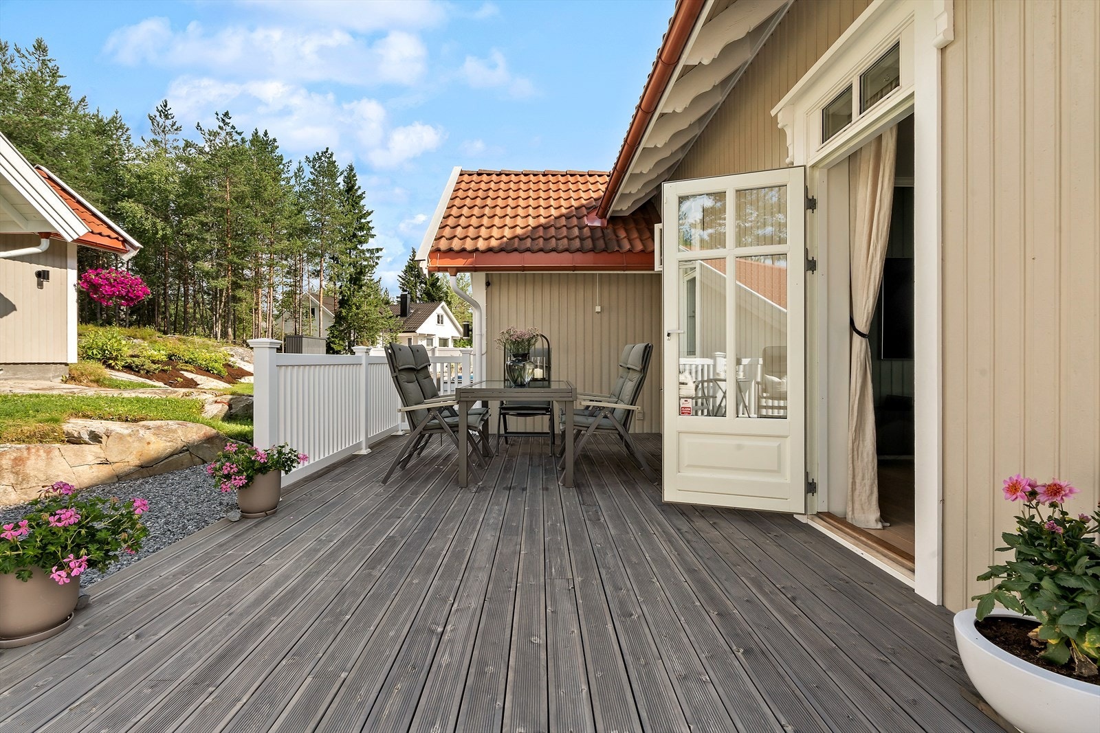 Det er utgang fra stuen til en stor terrasse og utgang til hage. Galleribilde