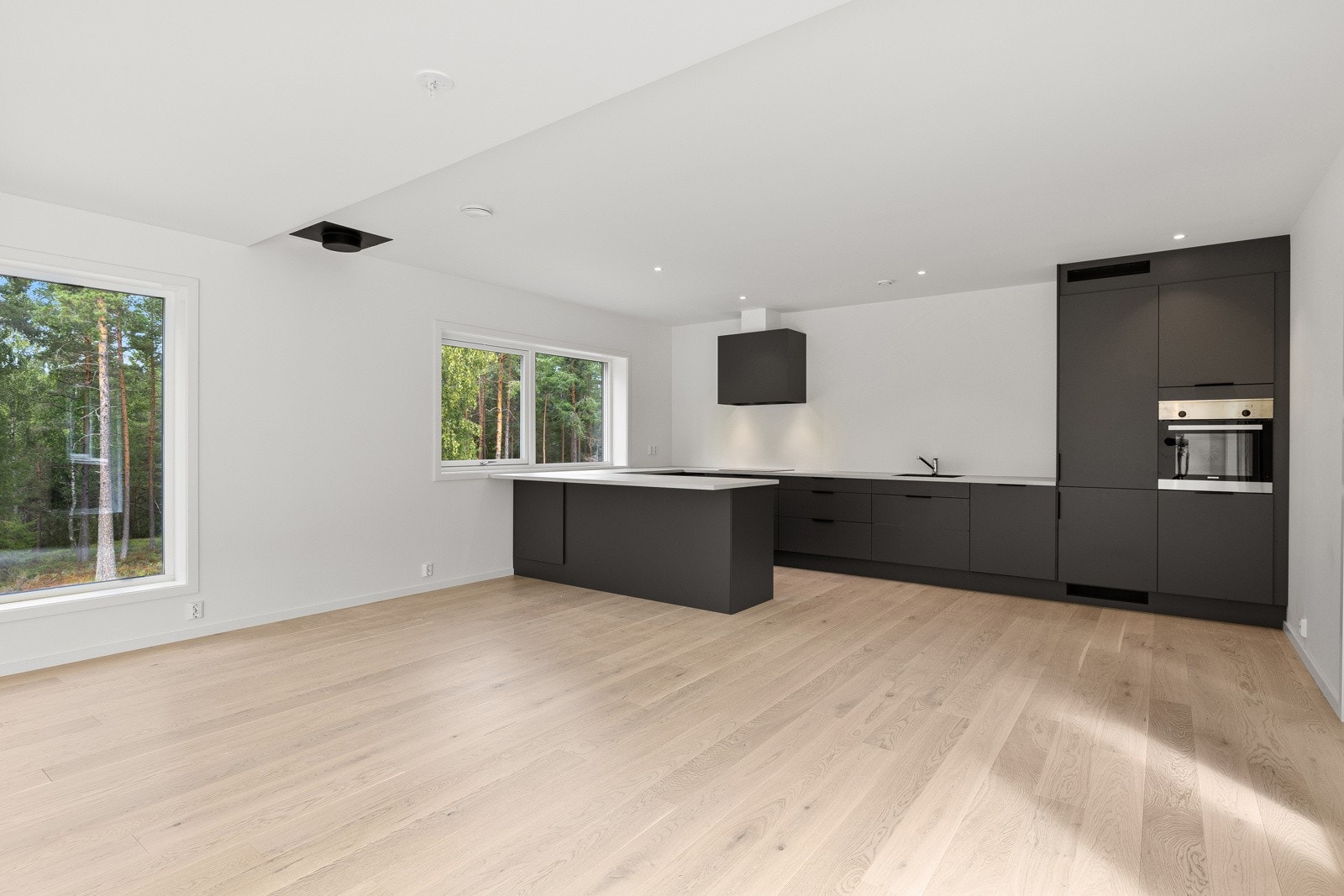 Huset har et lekkert kjøkken med glatte mørke fronter og benkeplate i laminat Galleribilde
