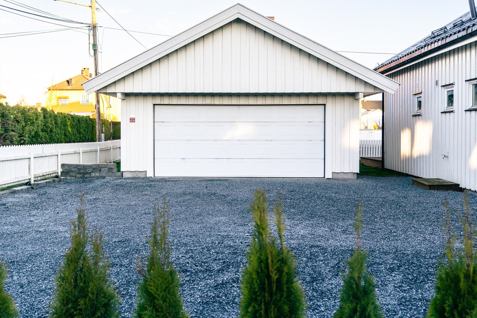 Frittstående garasje med dobbel port og gruslagt innkjørsel. Galleribilde