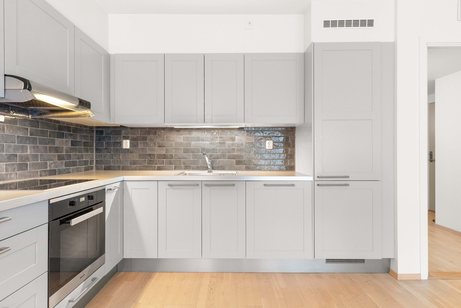 Belysning under overskap, samt fliser på vegg over benkeskap. Galleribilde