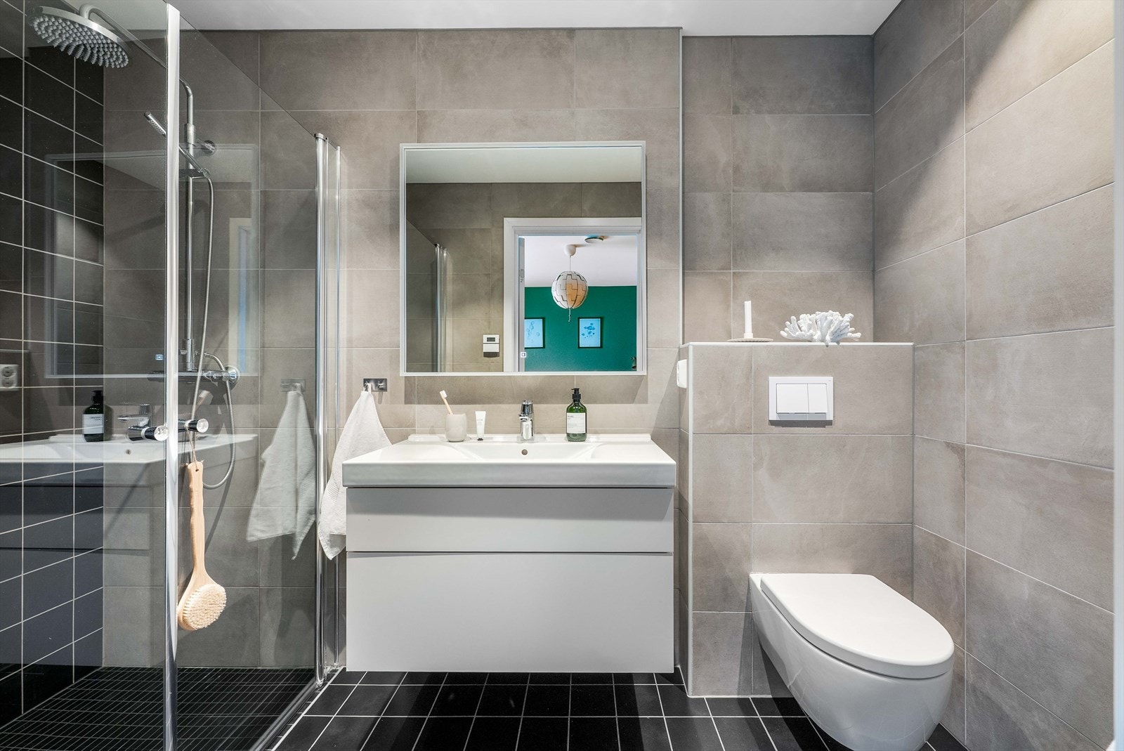 Badet i tilknytning til hovedsoverommet er pent flislagt med underliggende varme i gulv. Badet er videre innredet med regnfallsdusj m/innfellbare glassdører, heldekkende servant, servantskuffer, speil og vegghengt toalett. Galleribilde