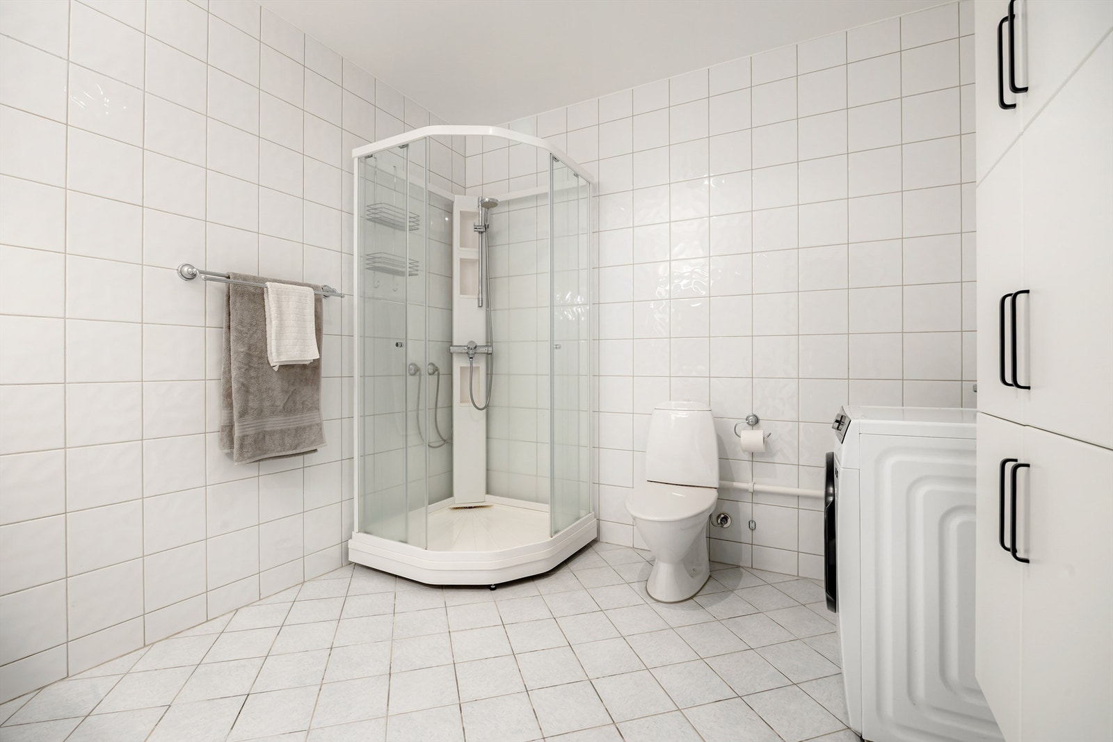Badet har dusjkabinett, gulvstående toalett og opplegg for vaskemaskin Galleribilde