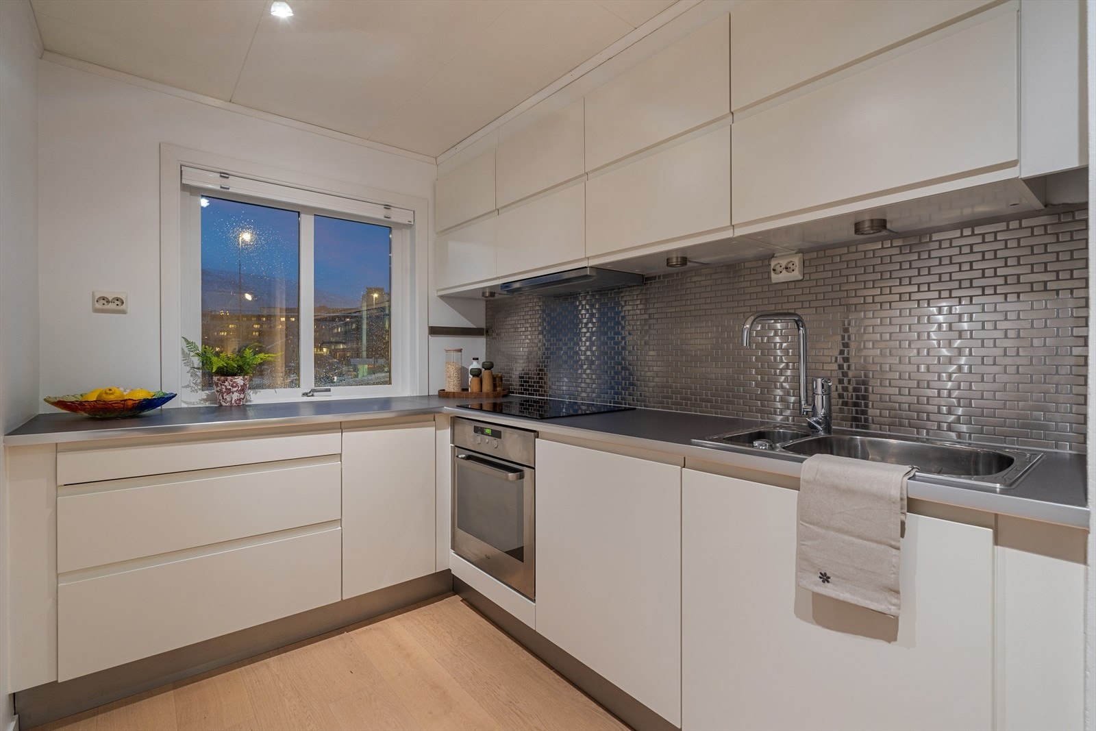 Delikat kjøkken med glatte fronter og laminat benkeplate og fliser over benk. Galleribilde