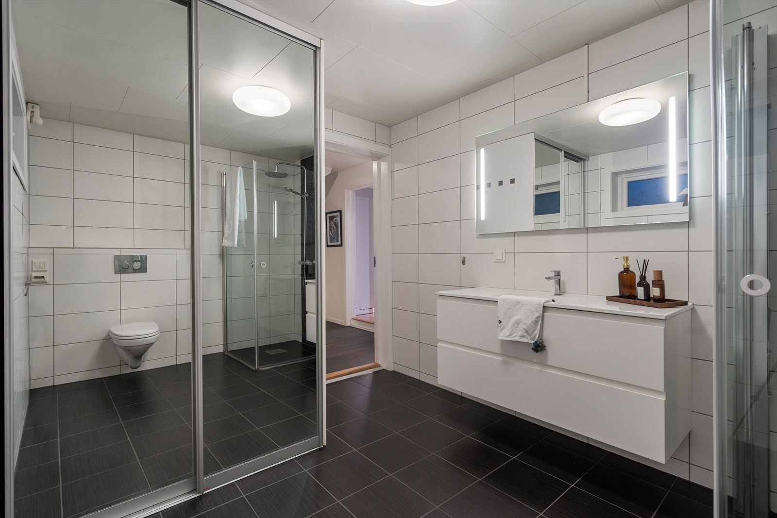 Rommet har innredning med nedfelt servant, veggmontert toalett, dusjvegger/hjørne og opplegg for vaskemaskin. Galleribilde