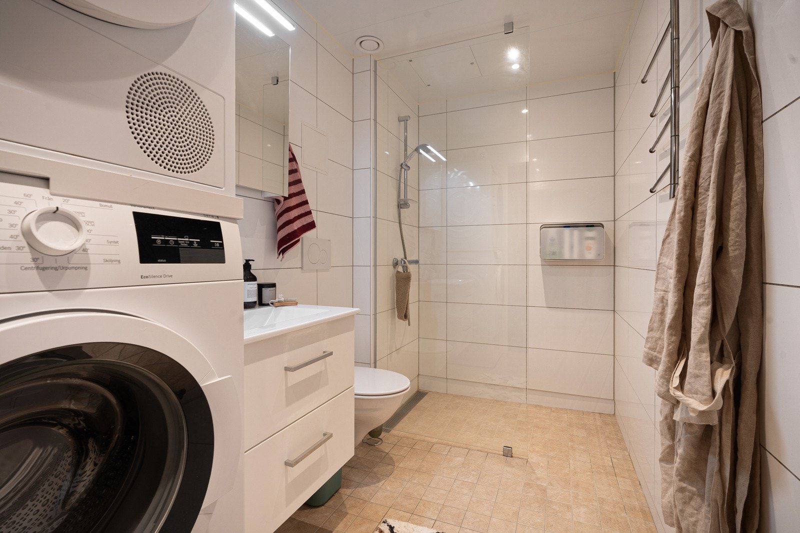 Flislagt og moderne bad av fin størrelse med plass til både vaskemaskin og tørketrommel.
