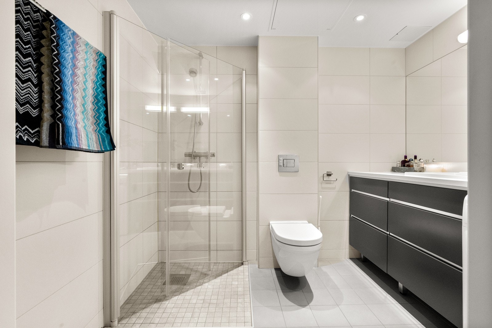 Leiligheten har et lyst og pent flislagt baderom. Baderommet har lyse fliser på gulv og vegger, elektrisk gulvvarme, downlights i himlingen og avtrekk via balansert ventilasjon. Galleribilde