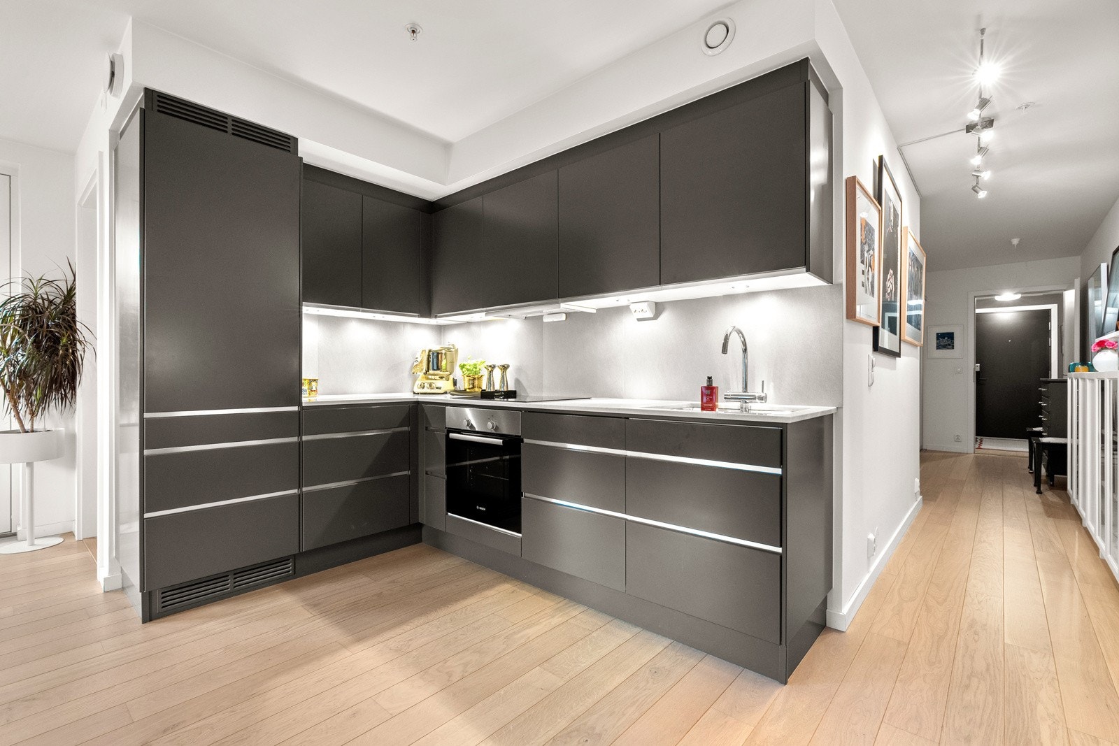 Stilren og moderne kjøkkeninnredning fra 2016 med god skap- og benkeplass. Innredningen har glatte mørke fronter og påkostet benkeplate av kompositt med nedfelt oppvaskkum. Galleribilde