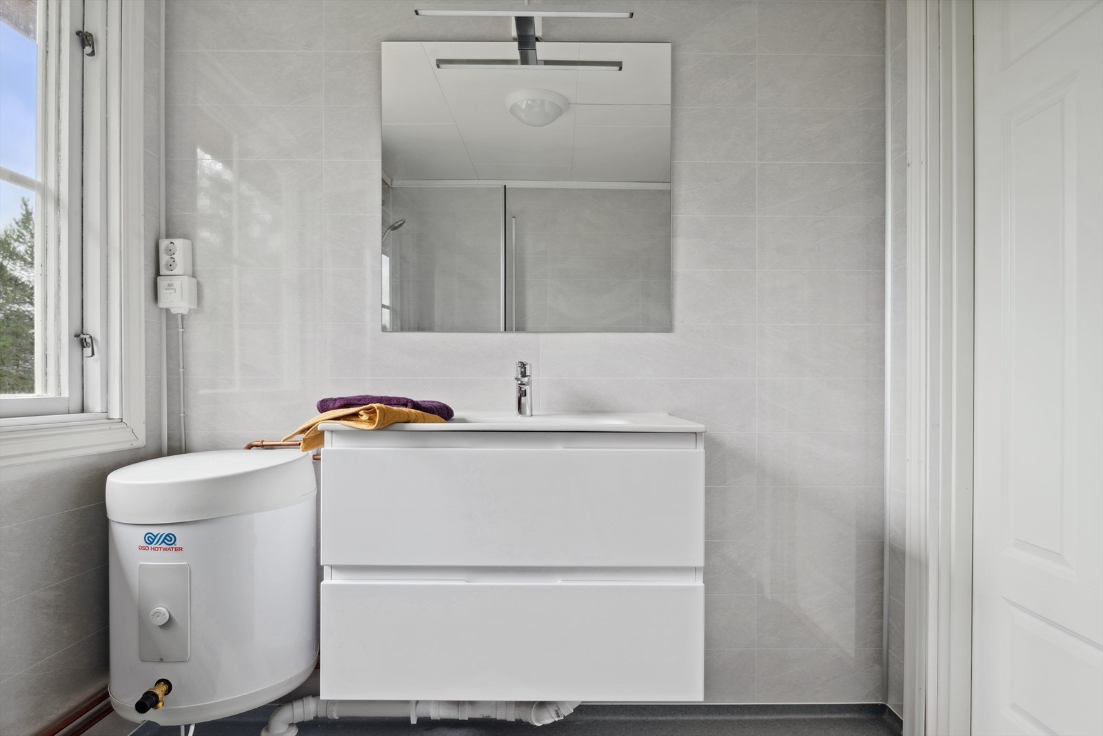 Baderommet har lysgrå plater på veggene og grått belegg på gulvet. Badet er helt nytt og har ikke vært i bruk. Galleribilde