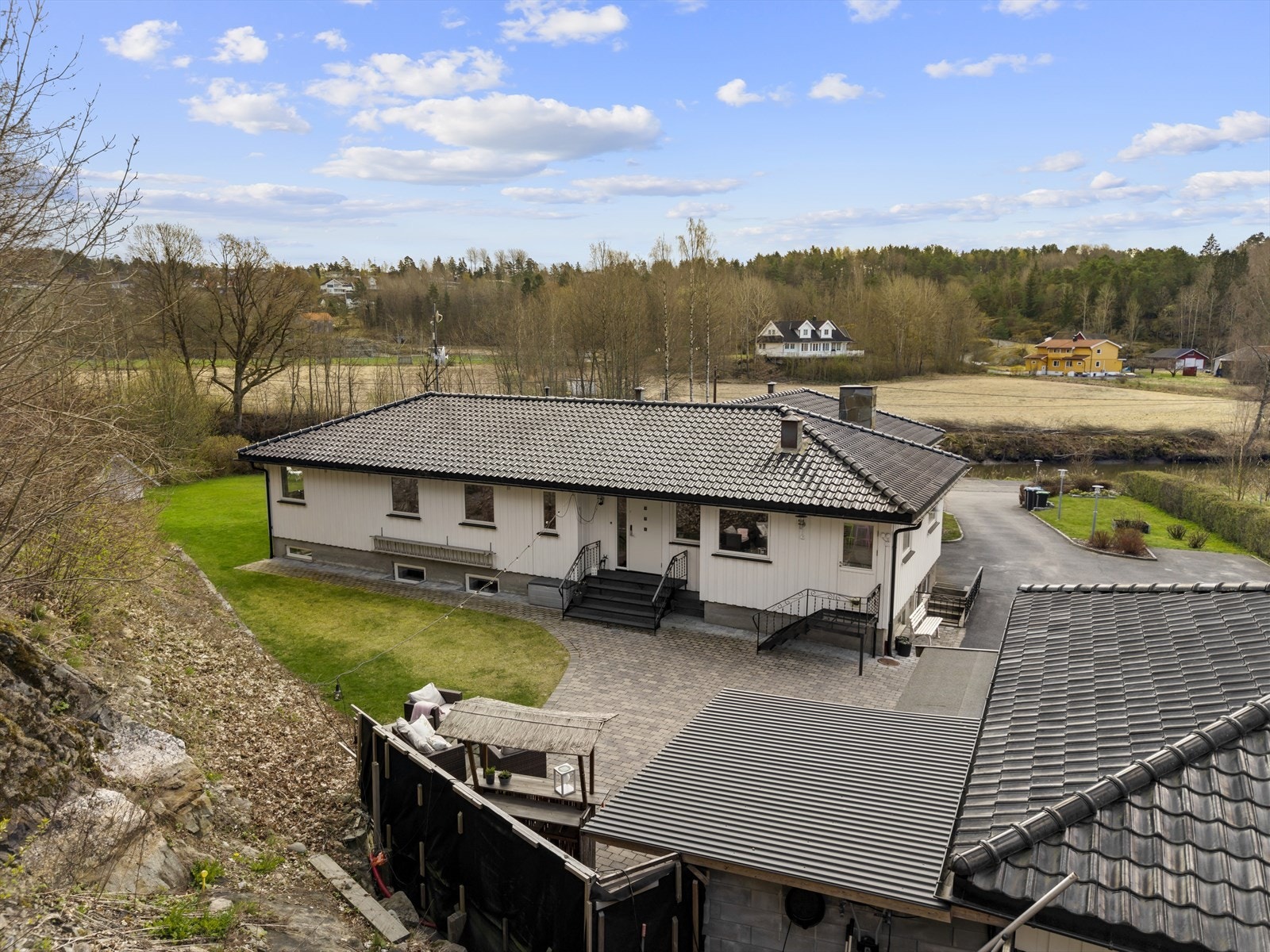 Det er steinlagt gårdsplass som er opparbeidet med plen og diverse grøntareal. Galleribilde