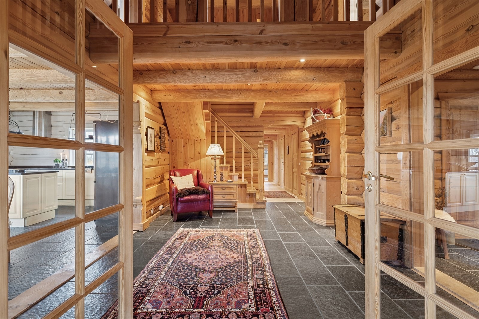 Innbydende hall, hyttas naturlige knutepunkt. Herfra har du adkomst til soveromsfløyen, stuen og kjøkkenet. Gulvet er belagt med skiferfliser med varmekabler, som gir både stil og komfort. Galleribilde