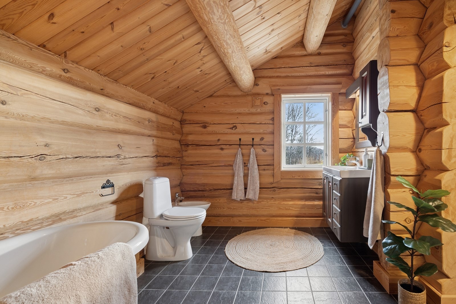 Midtpunktet er det flotte, frittstående badekaret - perfekt for lange, avslappende bad etter en dag ute i naturen. Rommet har også dusjkabinett, toalett og en stilfull servant med god oppbevaringsplass Galleribilde