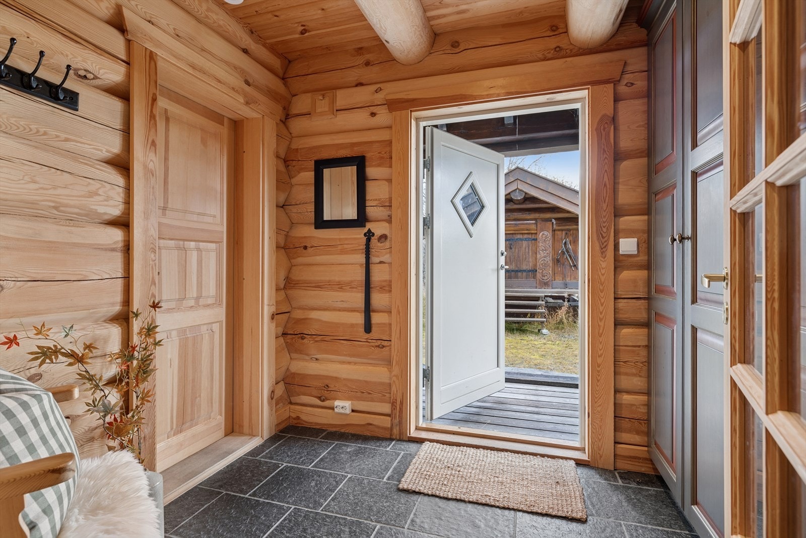 Entréen er romslig og innbydende, med skiferfliser på gulvet og varmekabler som gir behagelig varme året rundt. Her er det god plass til oppbevaring, inkludert garderobeskap, og direkte tilgang til vaskerom Galleribilde