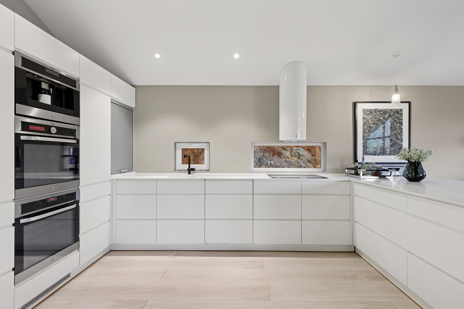 Integrerte hvitevarer som to stekeovner, kaffemaskin, vinskap, oppvaskmaskin og kjøl-/fryseskap. Galleribilde