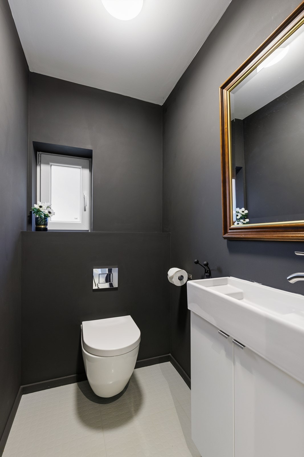 Eiendommen har et separat toalettrom med en enkel baderomsinnredning, speil og veggmontert toalett. Galleribilde