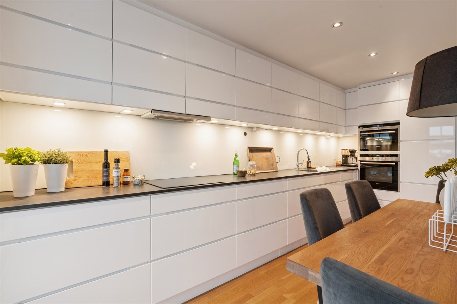 Kvik kjøkkeninnredning med praktisk belysning under overskap. Galleribilde