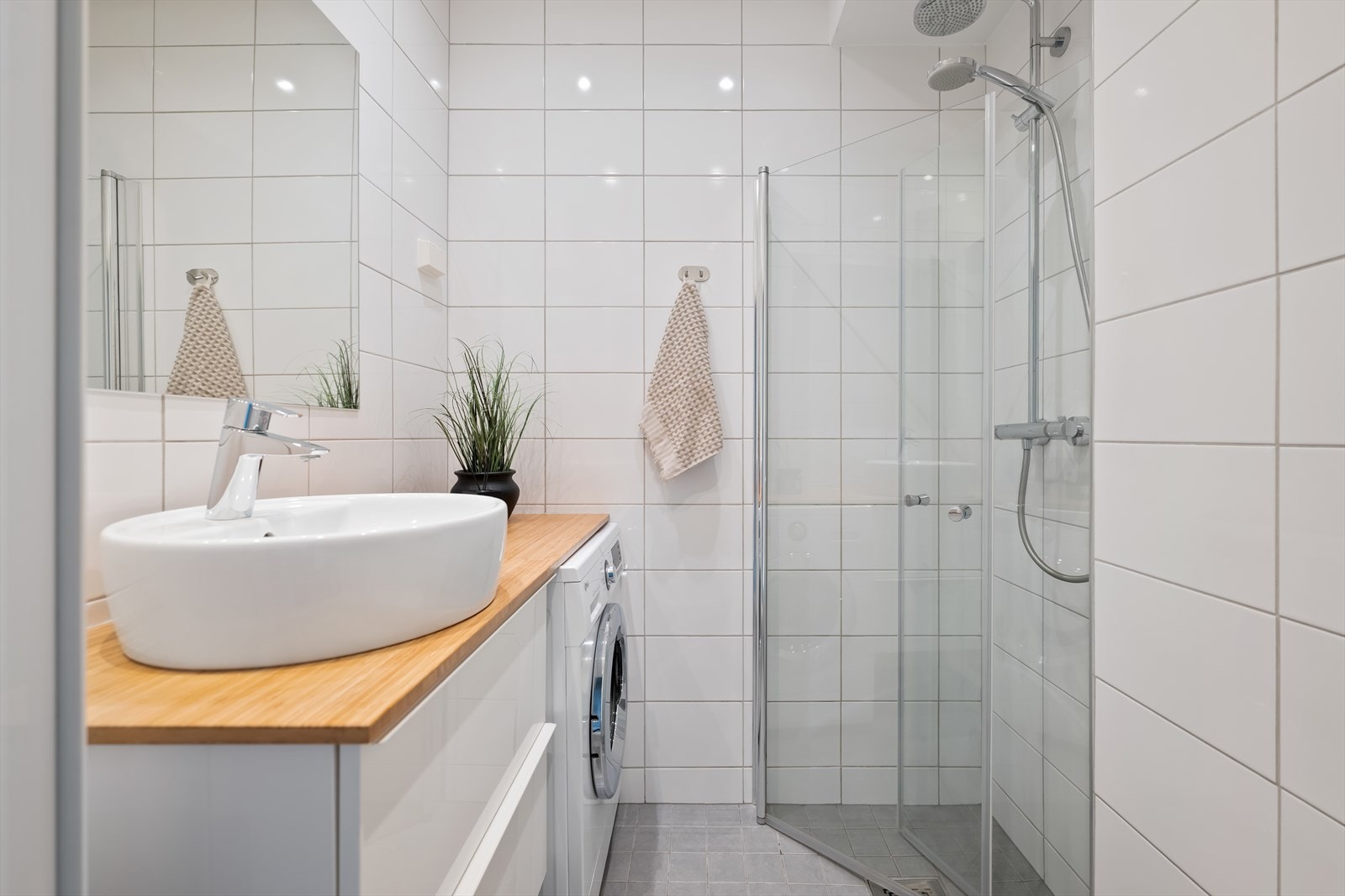 Dusjhjørne med svingbare glassdører gir en effektiv utnyttelse av baderomsarealet. Det er i tillegg montert opplegg for vaskemaskin. Galleribilde